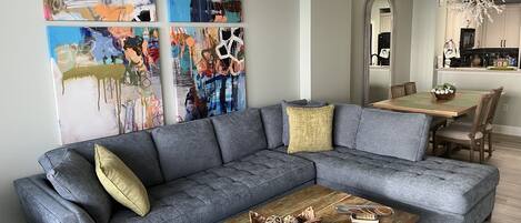 75 inch TV in Living room with a sectional sofa, chair with ottoman 
