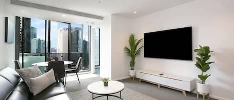 A very spacious living area with a 75 inch Samsung smart TV.
