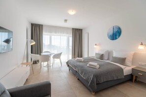 Another angle of the bedroom, showing the bed, a soft gray chair, and a minimalist design for a cozy atmosphere.

