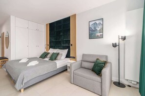 Another angle of the bedroom, showcasing the bed, a comfortable armchair, and soft lighting, emphasizing relaxation.
