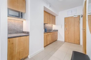 A compact kitchen with wooden cabinets, a gray backsplash, and sleek appliances, offering a practical and stylish design.
