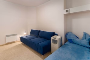 Another seating area with a blue sofa and simple furnishings, designed for comfort.
