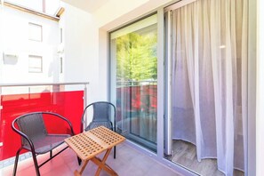 A balcony with red accents, outdoor seating, and a small table, perfect for enjoying fresh air.
