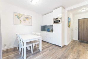 A dining area with a white table and chairs, adjacent to the kitchen, designed for comfort and convenience.
