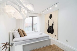 Another view of the living space, highlighting a cozy gray sofa, a modern floor lamp, and minimal decor.
