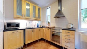 A modern kitchen with wooden cabinets, built-in appliances, and a dining area for four.
