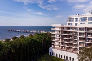 A scenic view of a modern building surrounded by greenery and overlooking the coastline.
