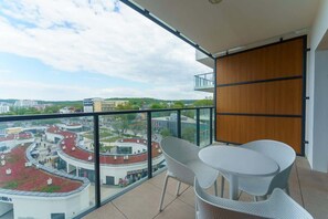 A balcony with outdoor seating and a stunning view of the city and sea.
