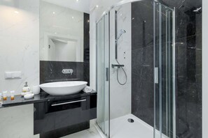 A sleek bathroom featuring black and white finishes, a glass-enclosed shower, and a modern vanity.
