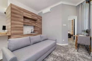 An open living area with a grey sofa, wooden accent panels, and a plush rug.
