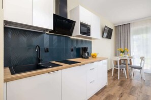 A modern kitchen with dark teal backsplash, white cabinets, and wooden countertops.
