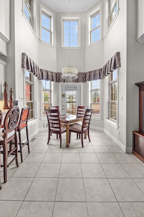 Bright and spacious dining area with high ceilings and a cozy fireplace, perfect for family dinners.