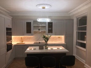 Beautiful high-end, quality bespoke kitchen. Elegant tiered lighting.