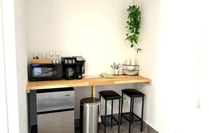 Kitchenette with coffee maker, microwave, mini fridge, coffee cup, wine glasses and silverwares.