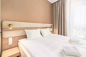 A minimalist bedroom with a comfortable double bed, soft bedding, and a neutral color palette, offering a calm and relaxing ambiance.
