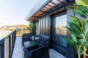 A balcony with outdoor seating, a table, and potted plants, perfect for enjoying the fresh air.
