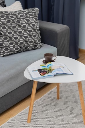 A close-up of the coffee table with a decorative plant and a cozy grey sofa in the background.
