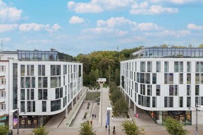 A modern residential complex with symmetrical buildings and a tree-lined courtyard.

