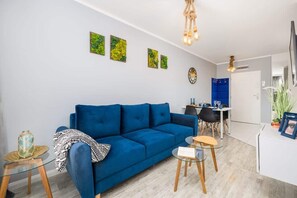 A living room with a blue sofa, a round coffee table, and bright green wall art.
