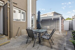 The back patio is set for alfresco dining, with an umbrella for shade.