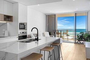 The sleek kitchen is designed around a breakfast bar and comes equipped with high-quality appliances and cooking utensils.
