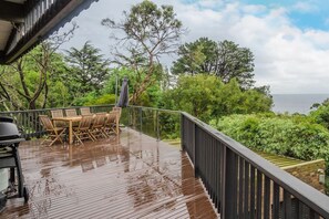 An expansive deck with a glimpse of the ocean view encourages meals outdoors with a BBQ ready to whip up a feast.