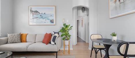 The dining area seamlessly connects to the living room, with beach photos gracing the walls to set the scene for a coastal atmosphere. Beyond the arched doorways, you'll find the kitchen, making this a perfect place to gather and dine.