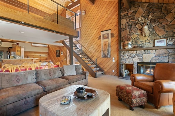 Living Room with Vaulted Wood Ceilings, a Cozy Sofa, TV (In Cabinet) Staircase leads to the Loft