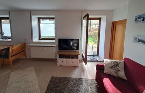 Ferienwohnung Almglück, separates Schlafzimmer, Küche, Terrasse, TV, WLAN-Wohnzimmer mit Samsung 43-Zoll-TV und Blick auf die Gartenterrasse.