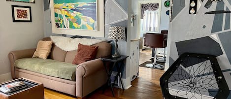 Eclectic living room with a comfy couch and lots of art.