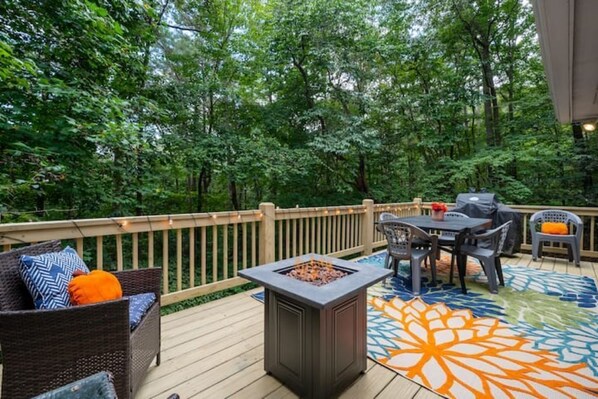Spacious deck with fire pit and gas grill surrounded by party lights. 