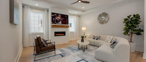 (1st Floor) Spacious living room with multiple seating, smart TV, and fireplace.