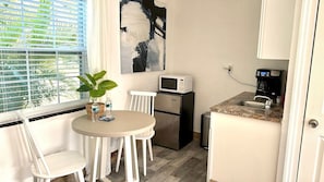 Kitchenette with coffee maker, microwave, mini fridge, coffee cup, wine glasses and silverwares.