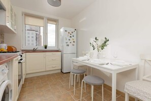 A compact kitchen with light cabinetry, a dining table, and decorative wall art.
