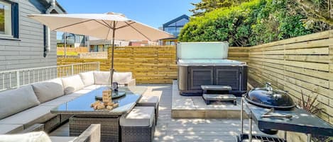 The deck area at the rear with rattan furniture, BBQ and private hot tub