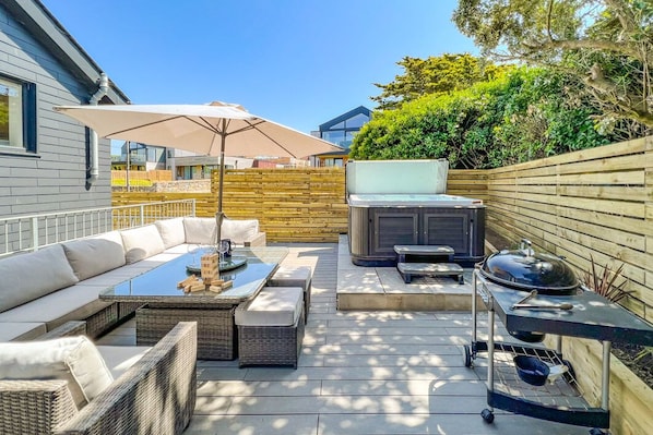 The deck area at the rear with rattan furniture, BBQ and private hot tub