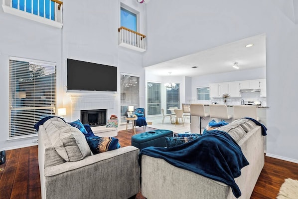 Spacious living room with high ceilings and a cozy fireplace, perfect for relaxing after a day out or an insurance relocation stay. Ideal for families with room to unwind and enjoy local dining like Brasao Steakhouse.