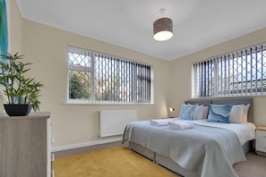 The room features a king-size zip and link bed, bedside tables with lamps, hangers, a mirror, and a hairdryer.