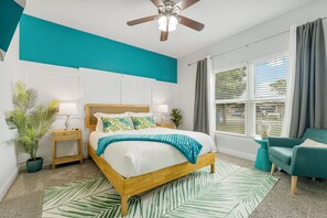 Charming bedroom with a teal accent wall, cozy bedding & warm, natural light!
