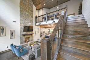 The stairs lead to the second-level loft-style game room/bunk room and two master suites.