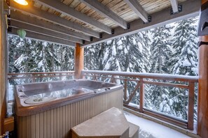 Retreat to the lower deck's private hot tub surrounded by snowy trees.
