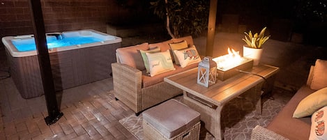 Private cozy patio with hot tub, fire pit, and decorative lights