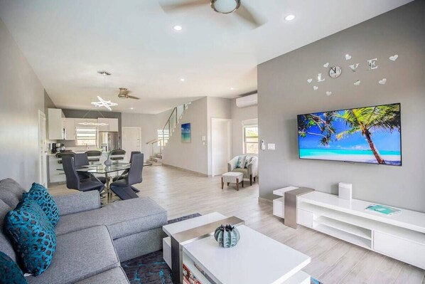 The living room features a comfy sofa and a 55” Smart TV