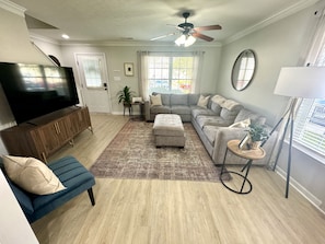 Living Room Bliss: Experience the Perfect Balance of Comfort and Entertainment in our Living Room, Featuring a Stunning 65-Inch TV as the Focal Point. Surrounding it, a Convenient Plush Padded Ottoman Create the Ideal Setting for Relaxing, Socializing, and Enjoying Your Favorite Shows or Movies in Style. Our sectional will fit your entire family.