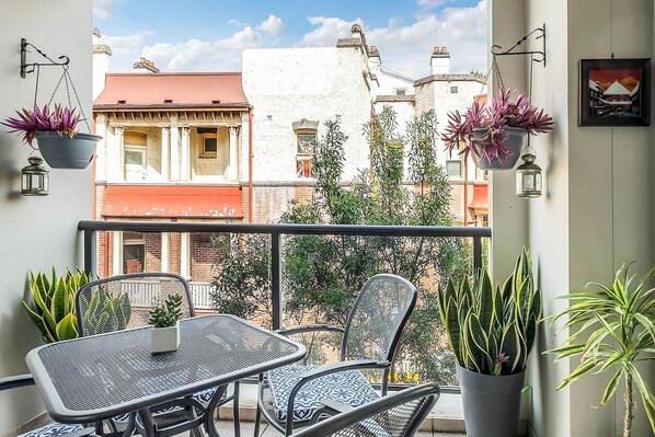 A private balcony features a four-seater table setting for outdoor dining.