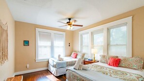 A roomy bedroom decorated out in bright colours, plush linens, and plenty of natural light.
