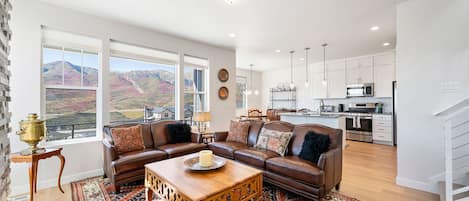 The spacious living area offers a breathtaking overlook of scenic mountain views through large windows.