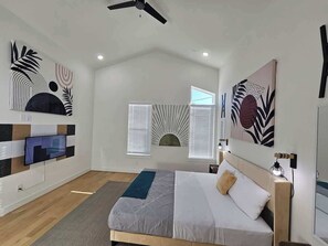 "Indulge in opulence within our immaculate Mid-Century Modern Master Bedroom. Featuring a generous king-size tan bed, three captivating art pieces, and chic hanging sconces, it exudes sophistication and luxury."