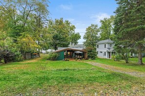 A captivating house facade surrounded by a lush green landscape, nestled in the midst of a wide-open space adorned with an abundance of plants and trees. The verdant surroundings enhance the charm of the green house, creating a harmonious blend of ar