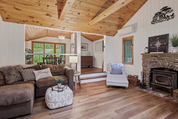 An open space living room characterized by comfy seating, a minimalist design aesthetic, and a strategically placed window offering a captivating view. The combination of comfort and simplicity creates a serene atmosphere, inviting residents and gues